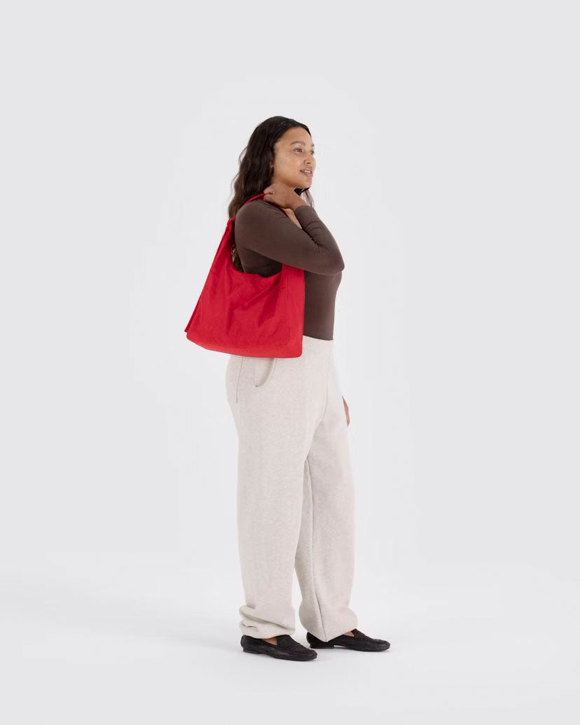 A close up of a person holding Person holding A Candy Apple recycled nylon Shoulder Bag from Baggu