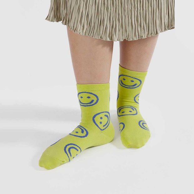 A pair of citron happy Baggu socks on feet