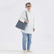 Person holding a Baggu horizontal zip duck bag in Navy Stripe over their shoulder