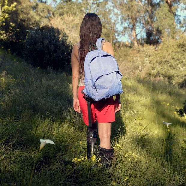 A person walking outside with A large recycled nylon backpack from BAGGU in the Pansy Blue colour way