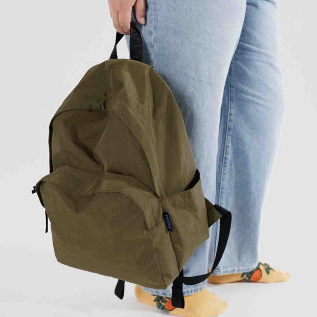 Person holding A large recycled nylon backpack from BAGGU in the Seaweed colour way by its top strap