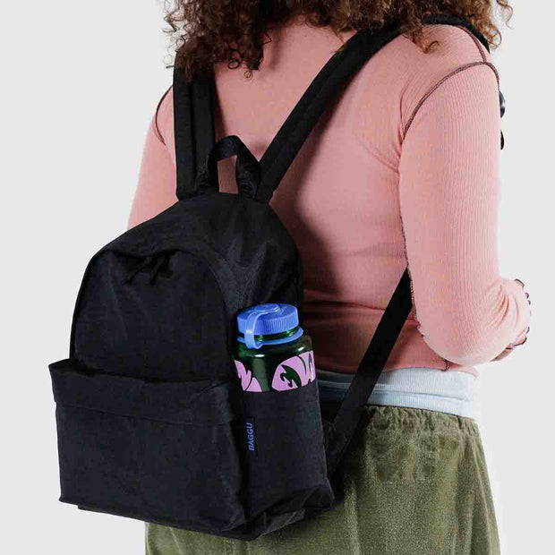 A person wearing A medium recycled nylon backpack from BAGGU in classic Black