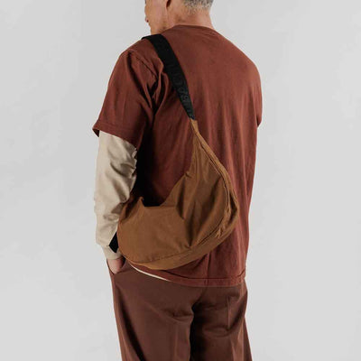 Man wearing the Baggu Brown medium Crescent bag over his shoulder