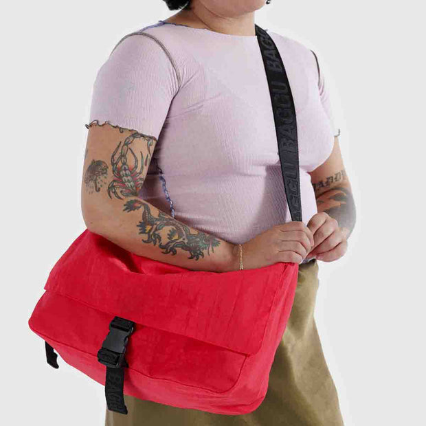 A person wearing a Baggu Recycled Nylon Messenger Bag in Candy Apple crossbody