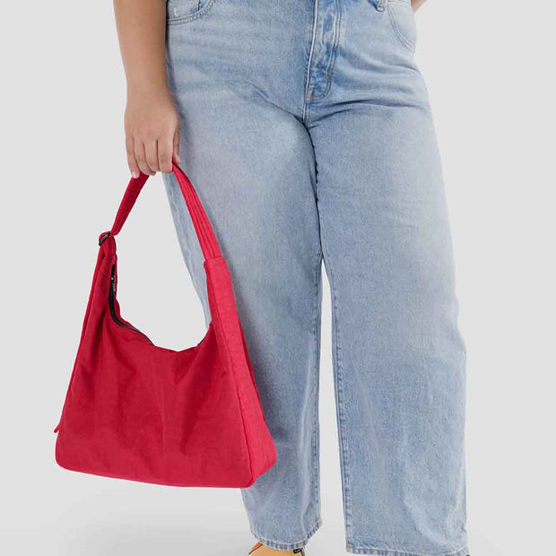 A close up of a person holding Person holding A Candy Apple recycled nylon Shoulder Bag from Baggu