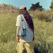 A lifestyle image of a person holding a nylon Shoulder Bag from Baggu in Digital Denim in a grassy area