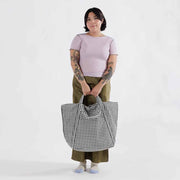 Person holding a Baggu Travel Cloud Bag in Black & White Gingham