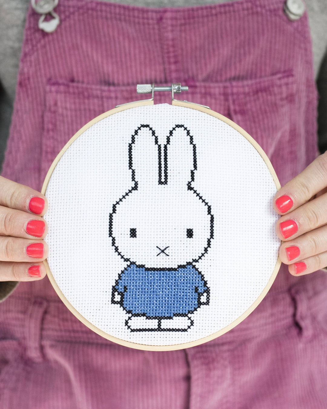 Person holding a cross-stitched Miffy bunny in an embroidery hoop.