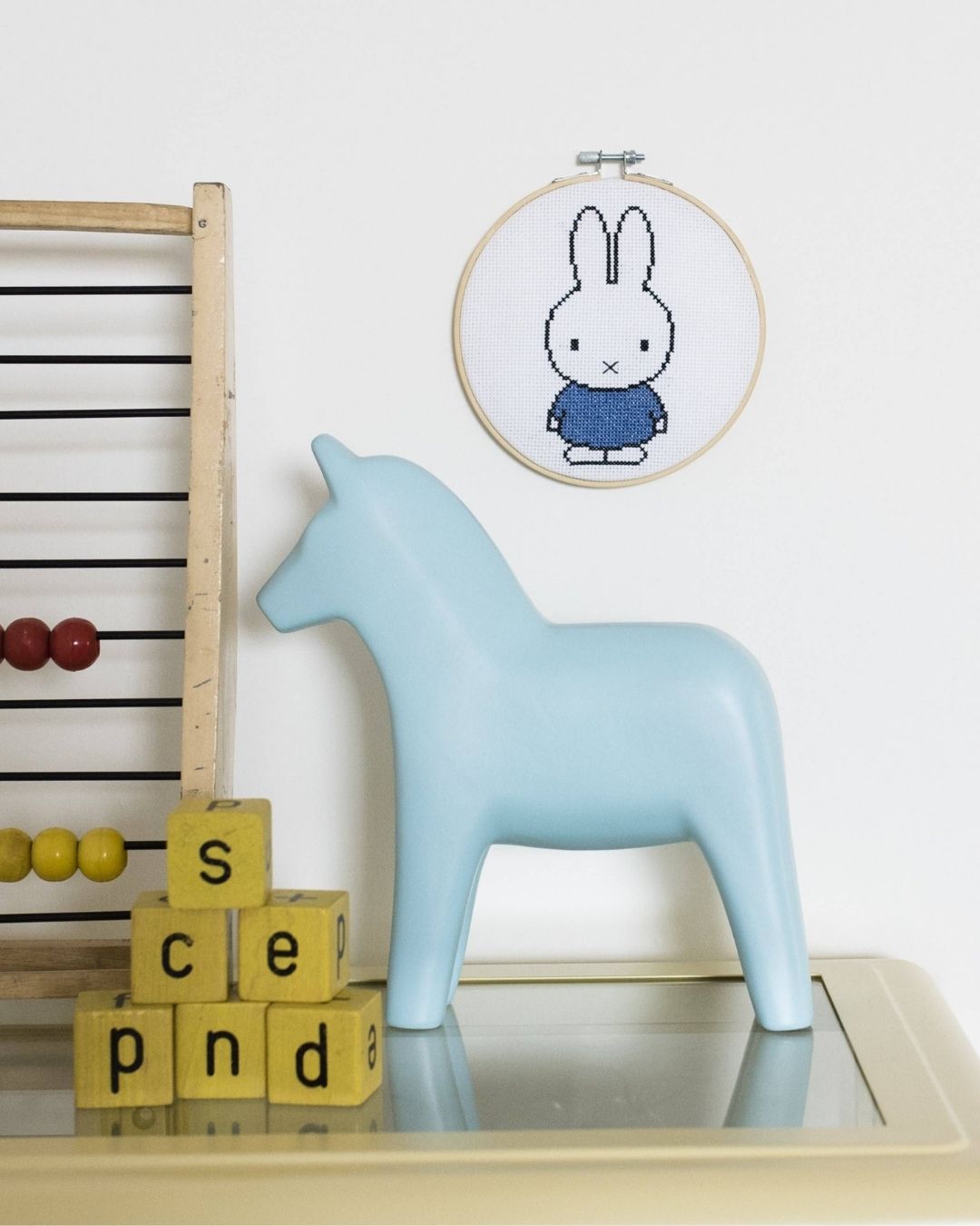 A cross-stitched blue Miffy bunny in an embroidery hoop.