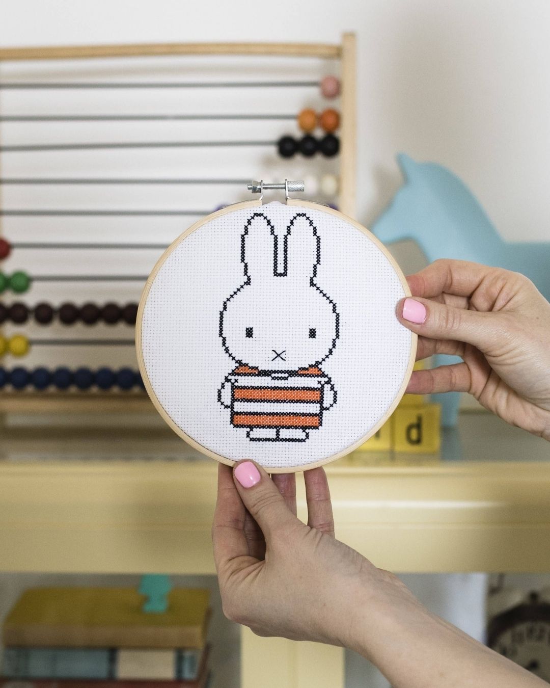A person holding Cotton Clara Stripy Miffy cross-stitch