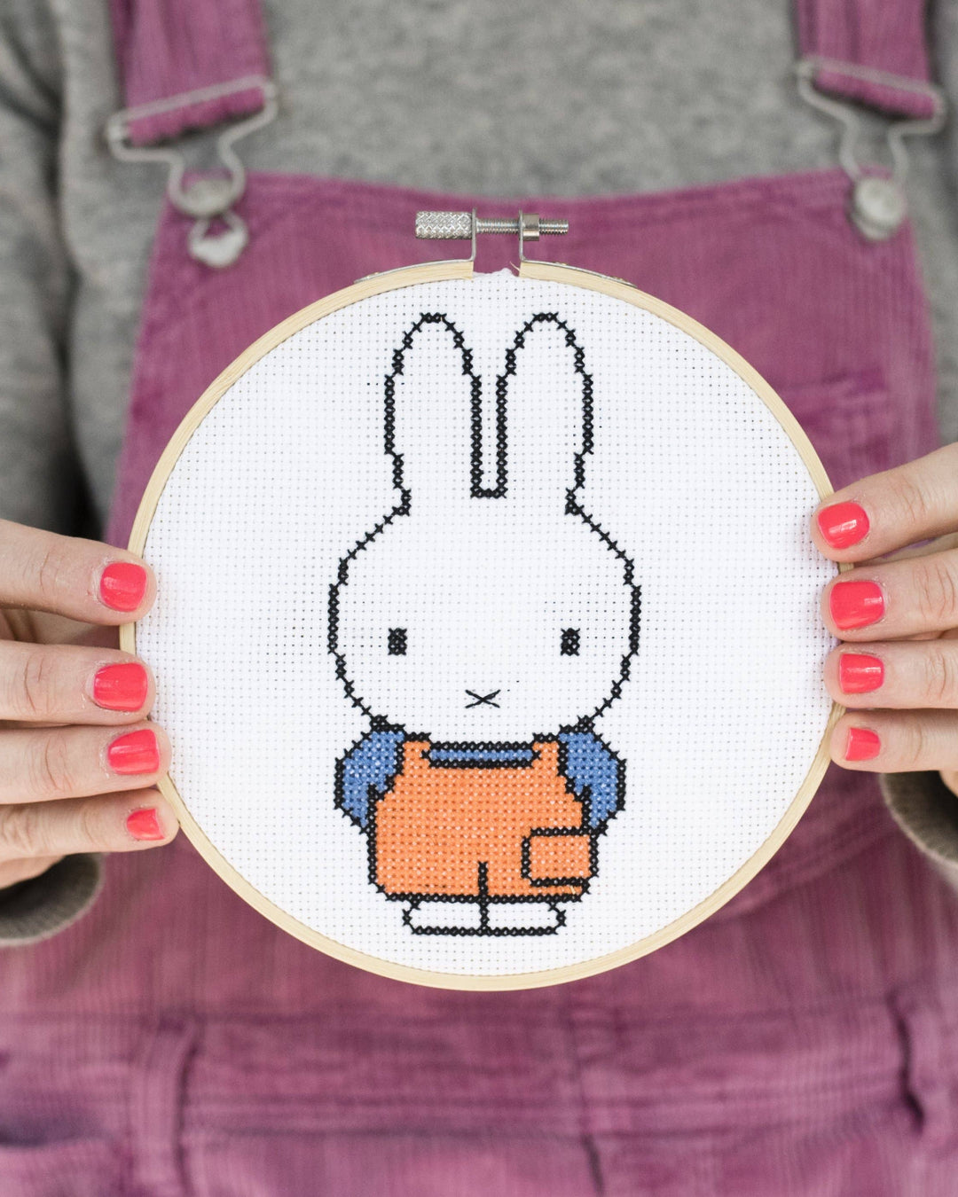 Person holding a cross-stitched Miffy bunny in an embroidery hoop.