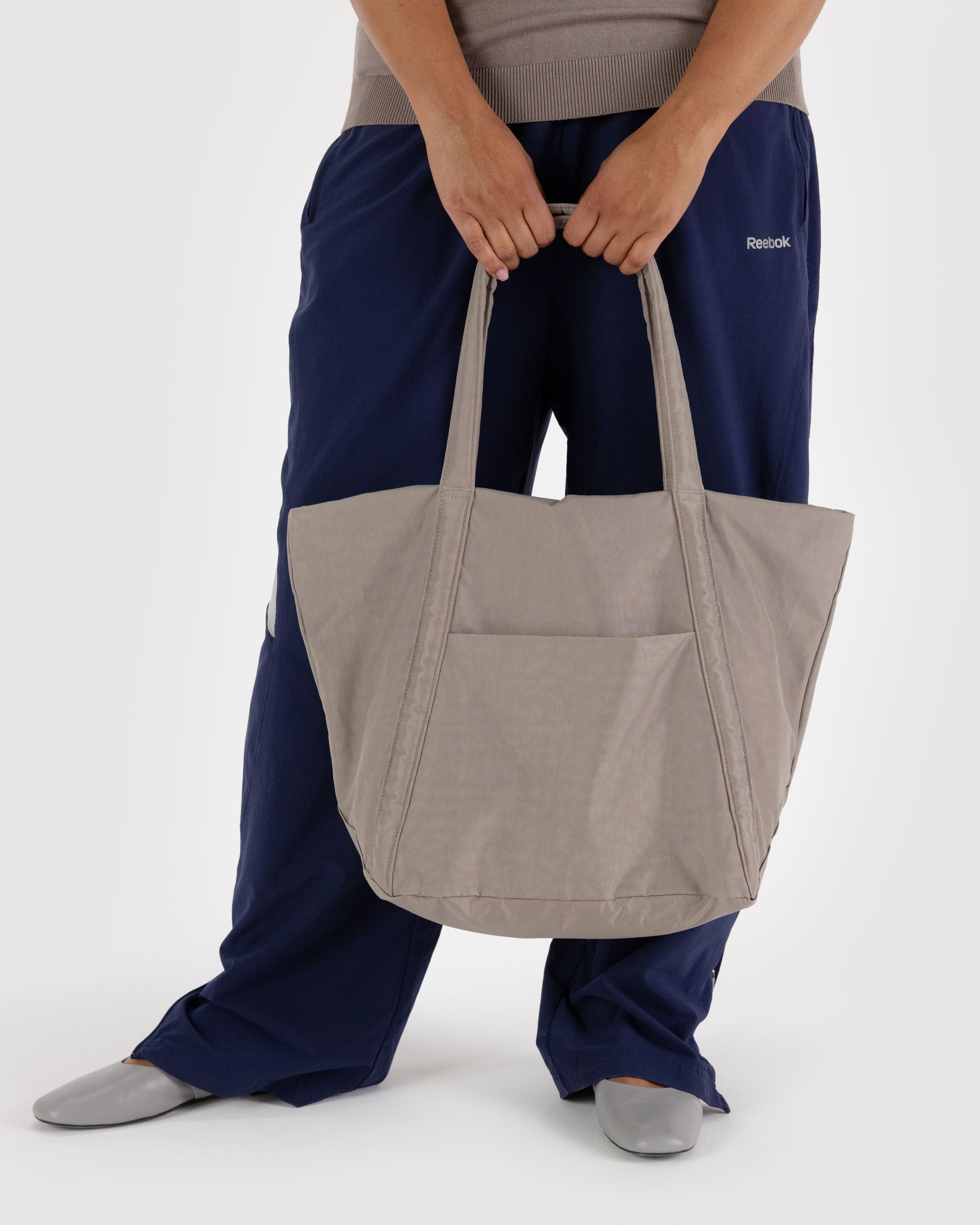 A person holding a BAGGU Cloud Bag in Dove in front of their body