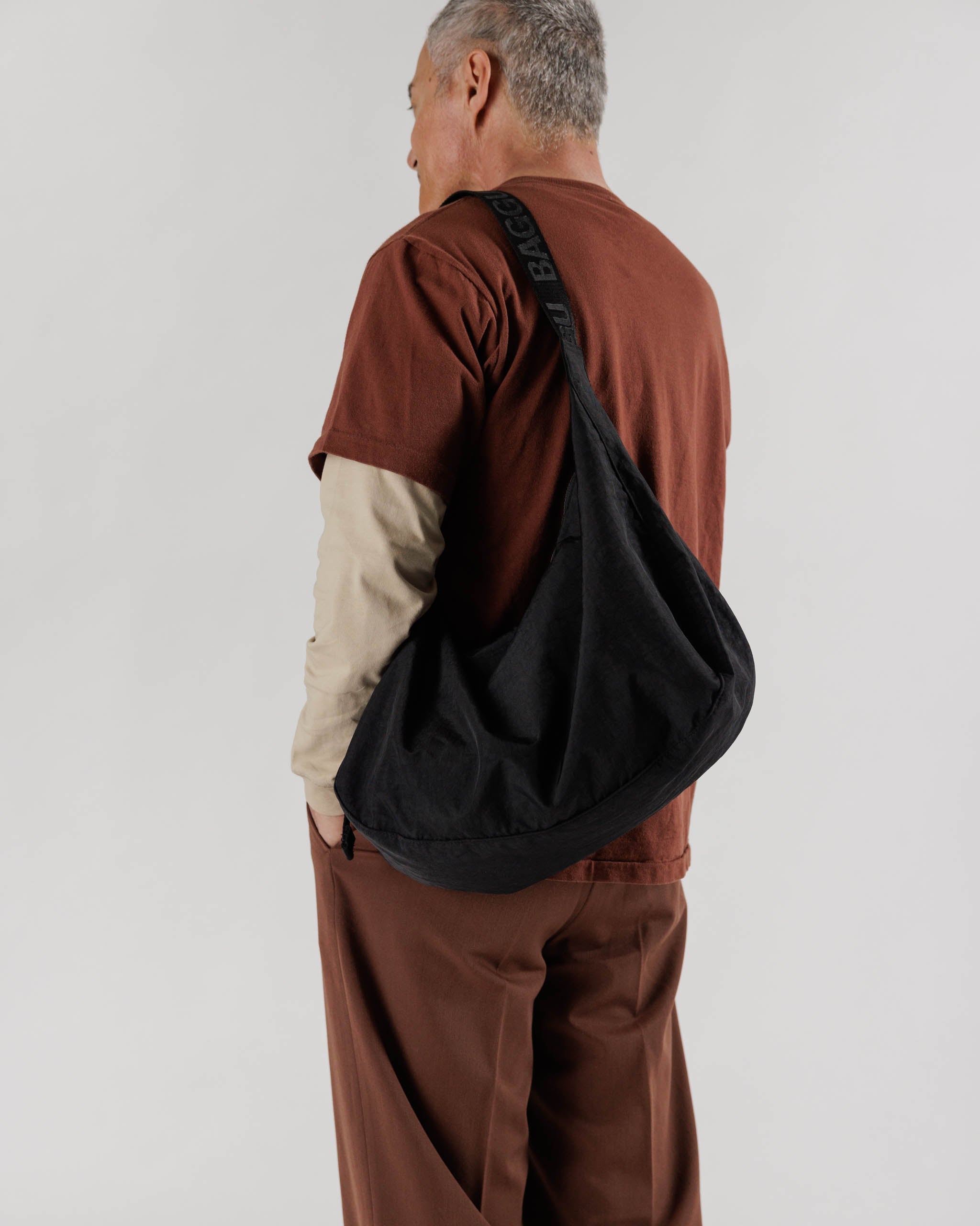 A person shown from the back wearing a large crescent bag in black 