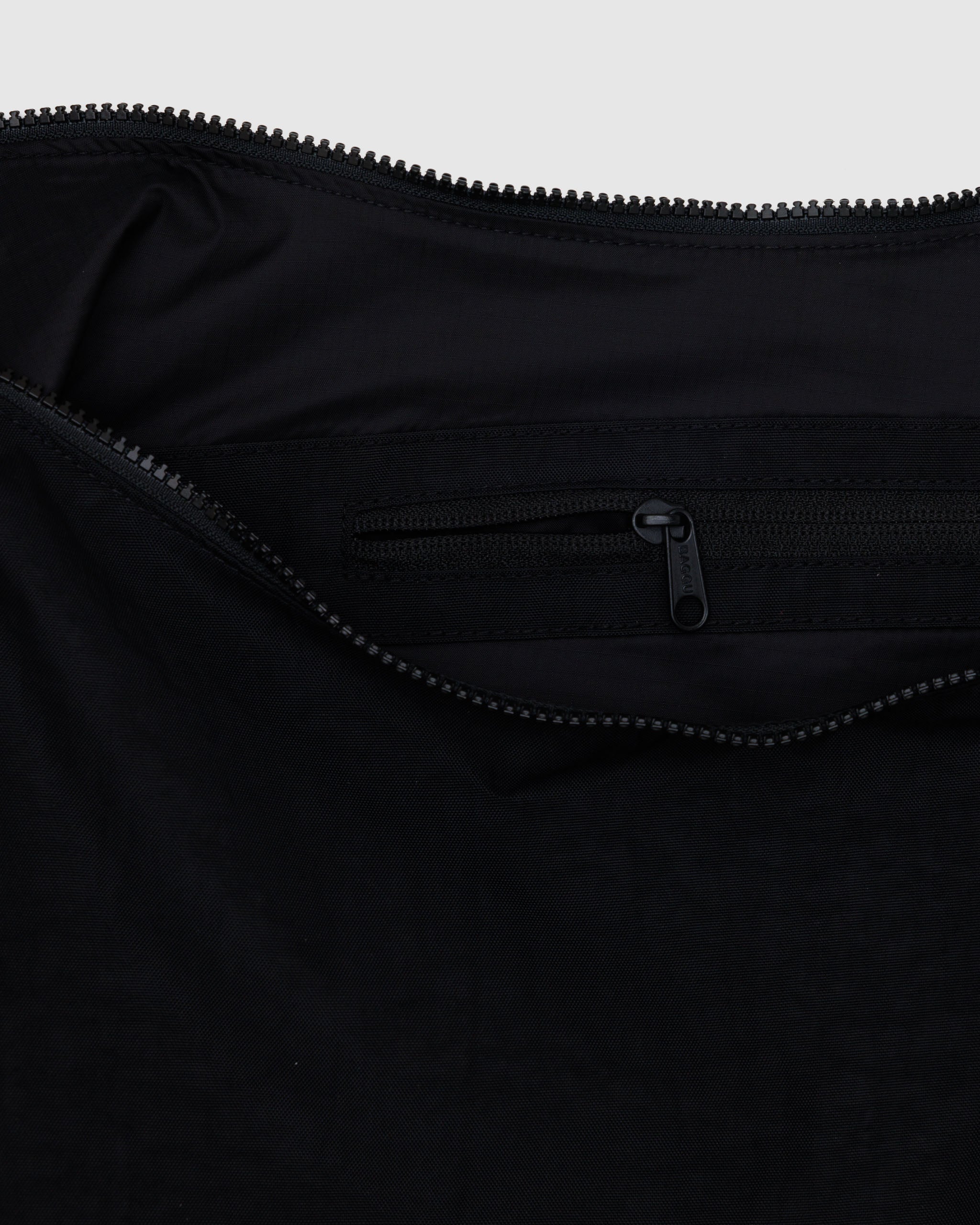 The inside zip of a large BAGGU Crescent Bag in Black