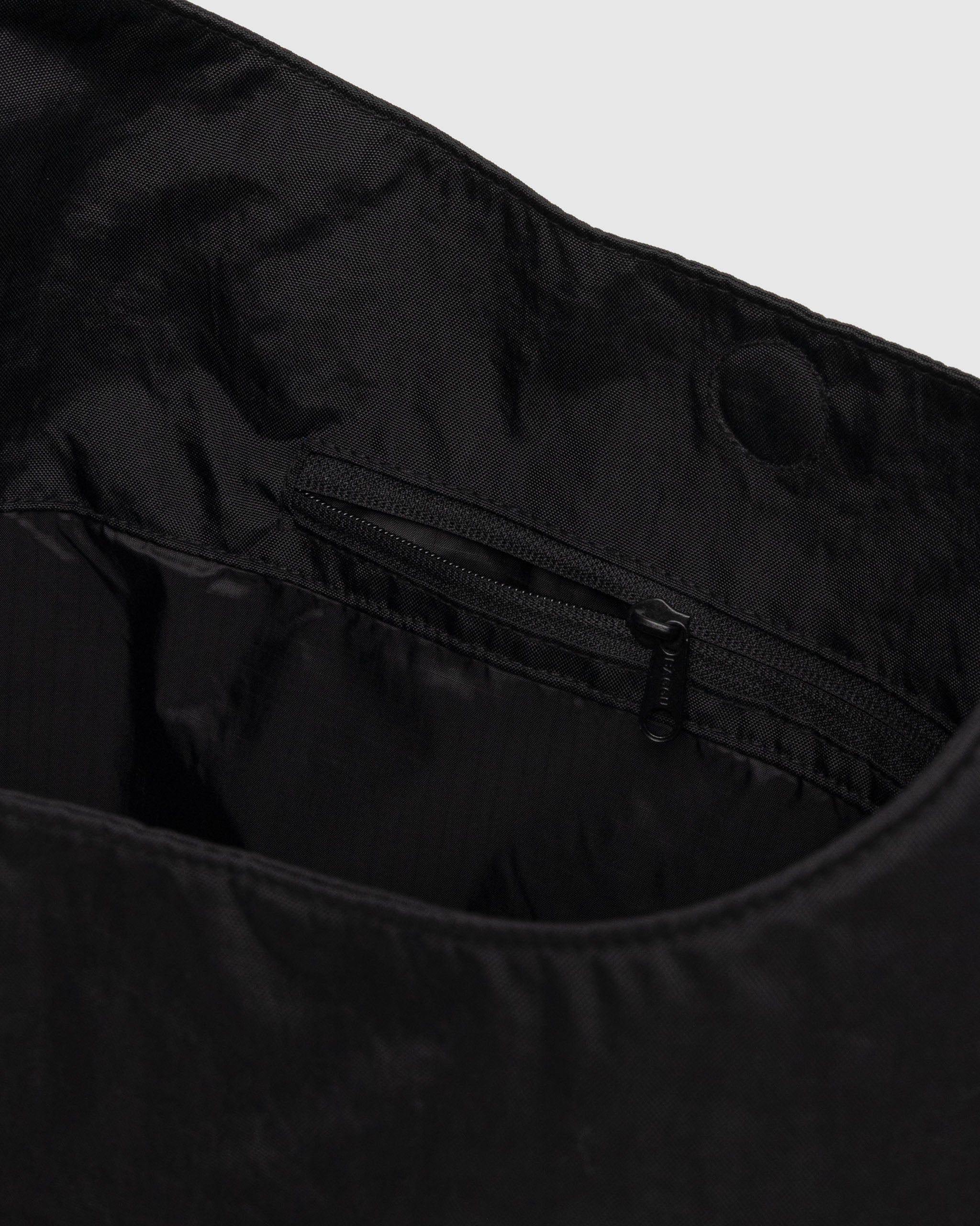 Interior pocket of a large nylon sling bag from Baggu in black