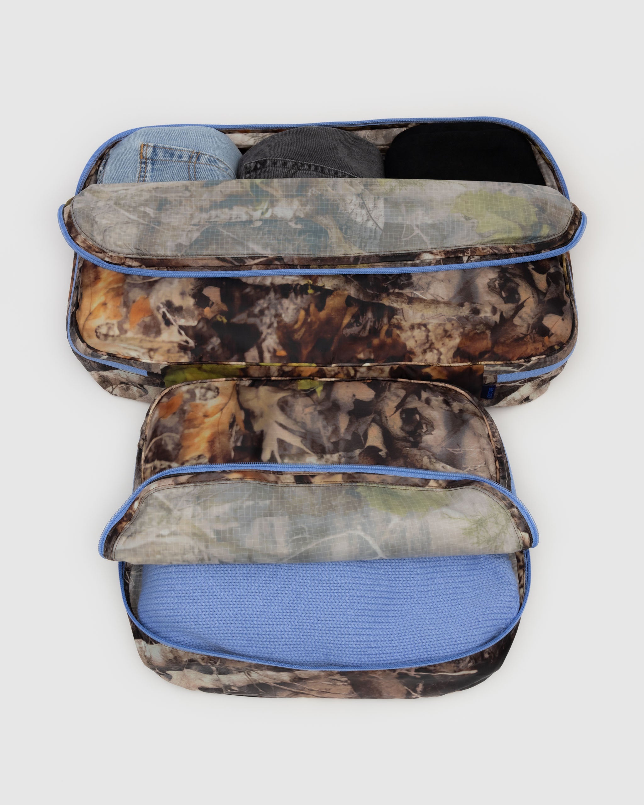 A set of large BAGGU packing cubes in Photo Forest open with contents shown open