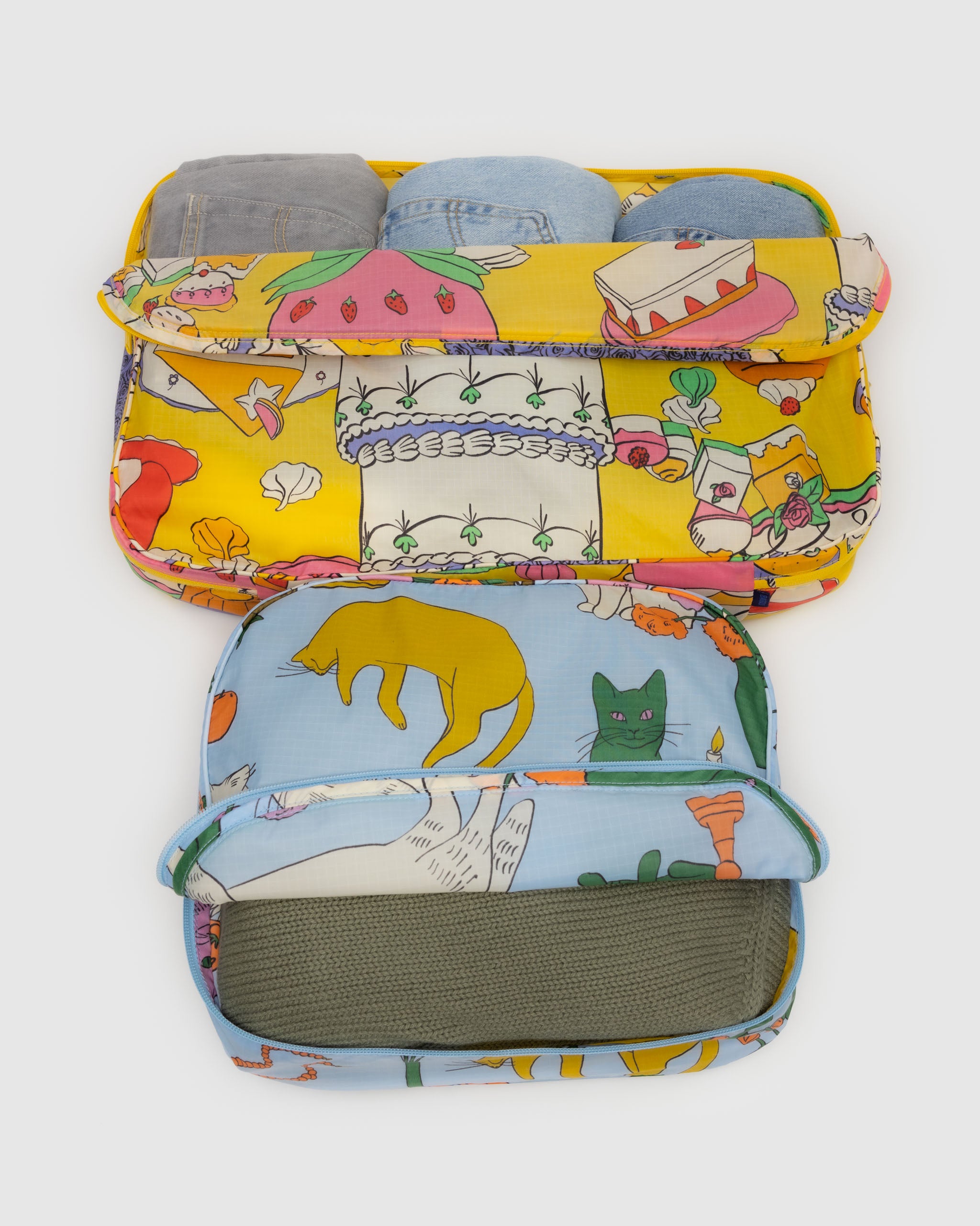 A set of large BAGGU packing cubes in Still Life shown in a suitcase