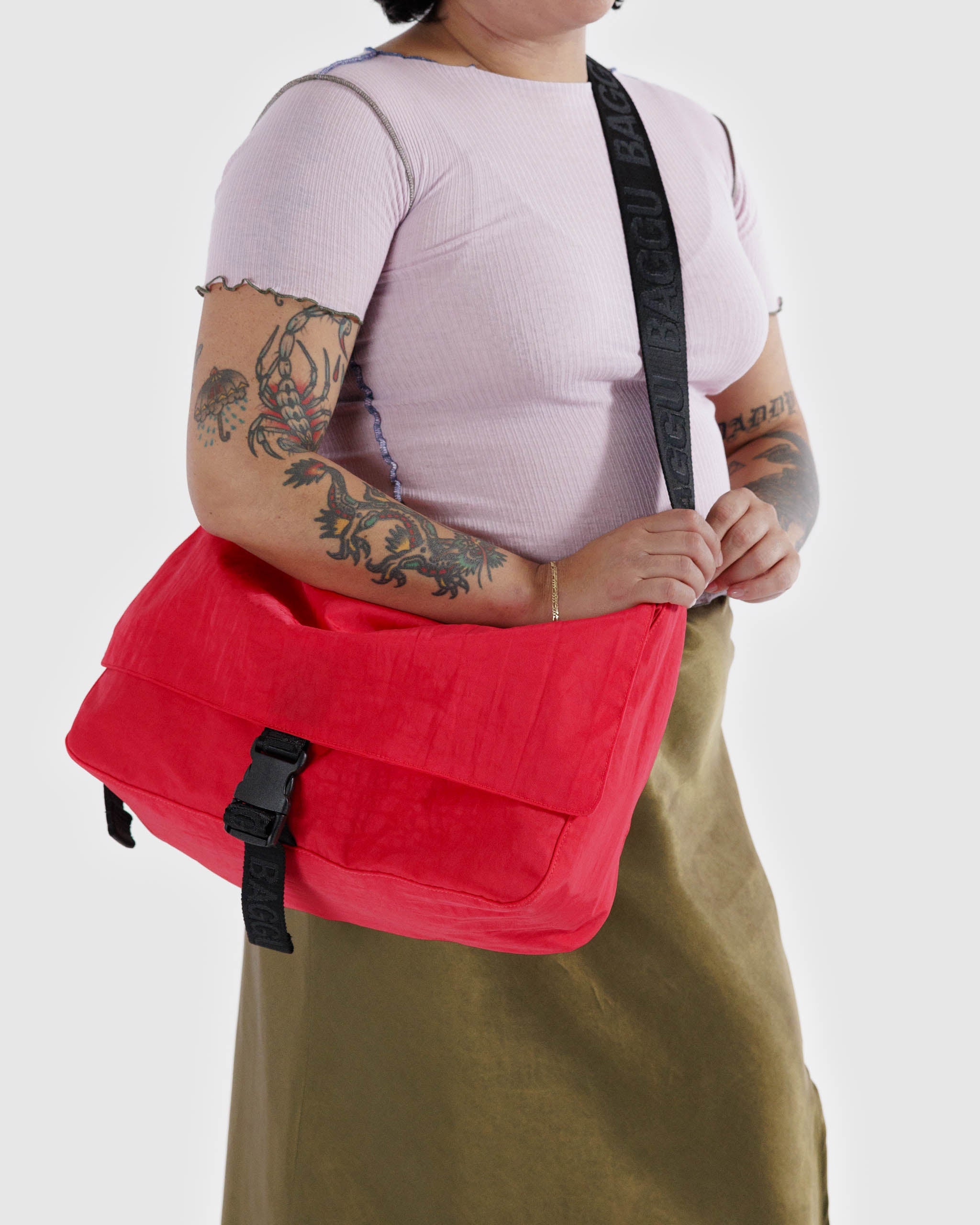 A person wearing a Baggu Recycled Nylon Messenger Bag in Candy Apple crossbody