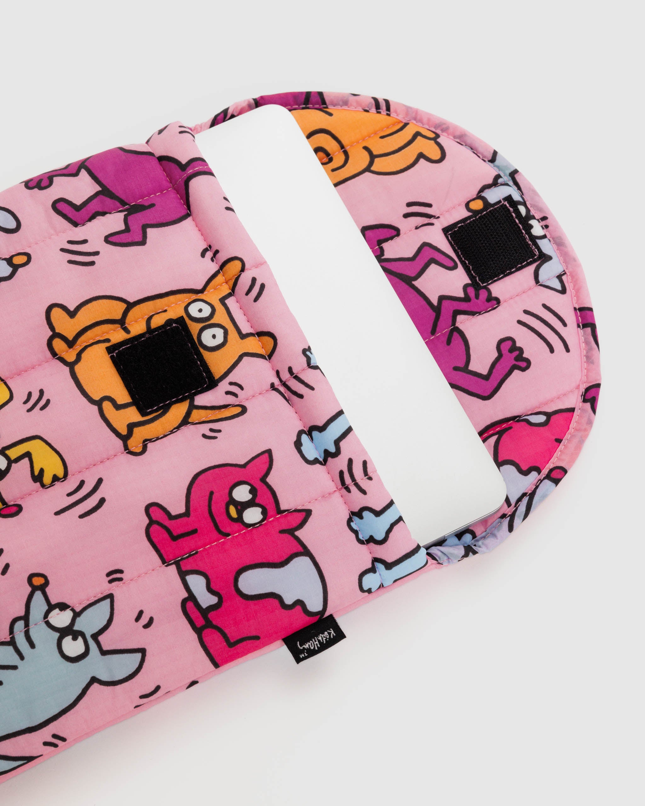 An open Keith Haring puffy laptop sleeve from BAGGU