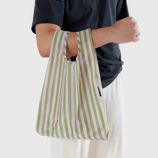 A person holding a Baby Baggu featuring the Avocado Candy Stripe design