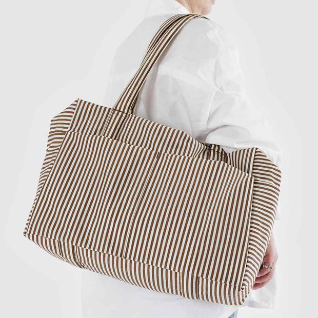 A Baggu Cloud Carry-On in Brown Stripe worn over the shoulder