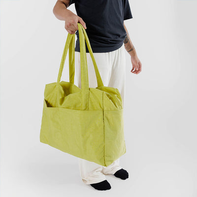 Person holding Baggu's Lemongrass Cloud Carry-on bag