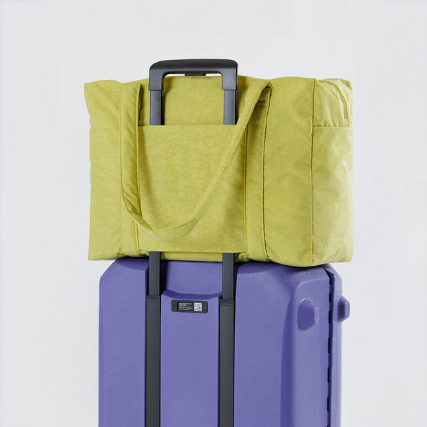 Baggu's Lemongrass Cloud Carry-on bag on suitcase