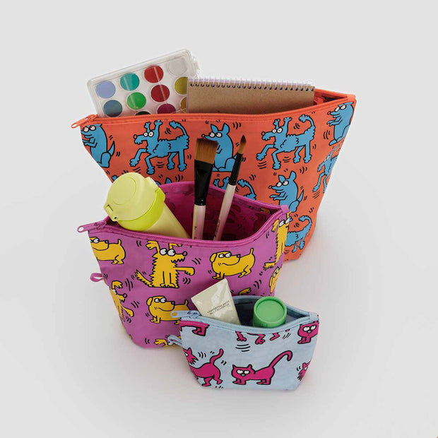 A BAGGU Keith Haring Pets Go Pouch set of three pouches shown open with art supplies in them