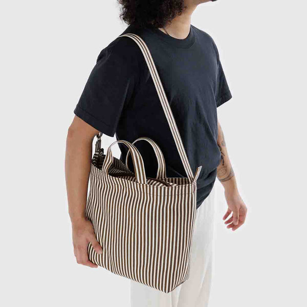 A person holding a Baggu Brown Stripe Horizontal Zip Duck Bag