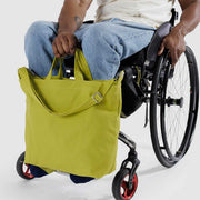 Person in wheelchair holding Baggu's Lemongrass horizontal zip Duck bag