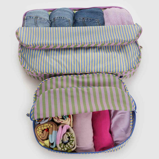 A set of two Baggu large packing cubes in the Hotel Stripe design shown open with clothing in them 