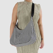 Close up of person holding A medium Crescent Bag from Baggu in Black & White Gingham