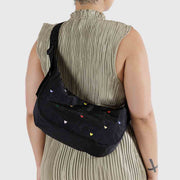 Close up of person wearing A medium Crescent Bag from Baggu in Embroidered Hearts