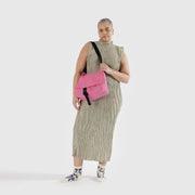 A person holding a Baggu Recycled Nylon Messenger Bag in Azalea Pink over their shoulder