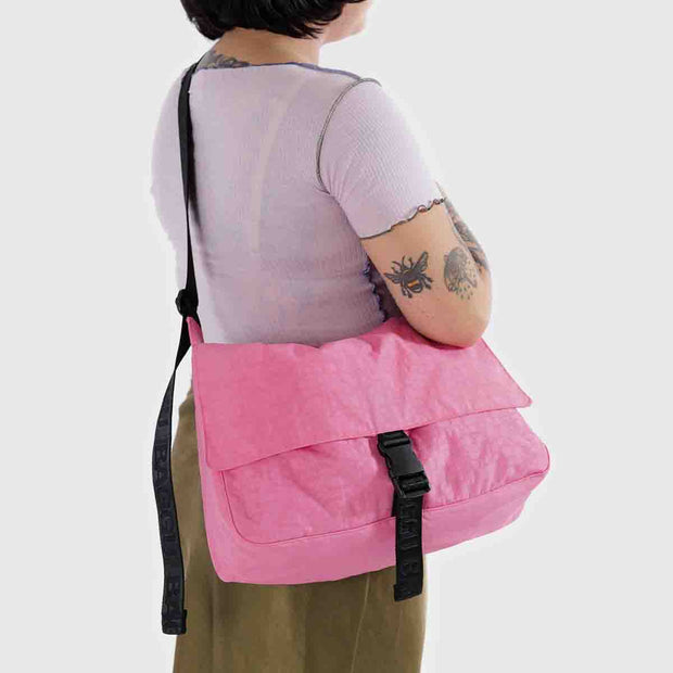 A person wearing a Baggu Recycled Nylon Messenger Bag in Azalea Pink crossbody