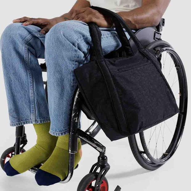 Person sat on a wheelchair holding a black mini cloud bag
