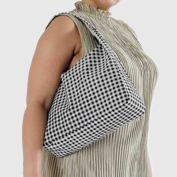 A woman holding a Black and White Gingham nylon Shoulder Bag from Baggu