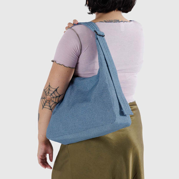 A person holding a nylon Shoulder Bag from Baggu in Digital Denim over their shoulder