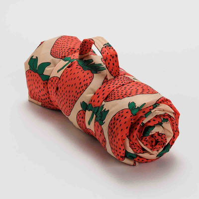 A Strawberry puffy picnic blanket from BAGGU rolled up
