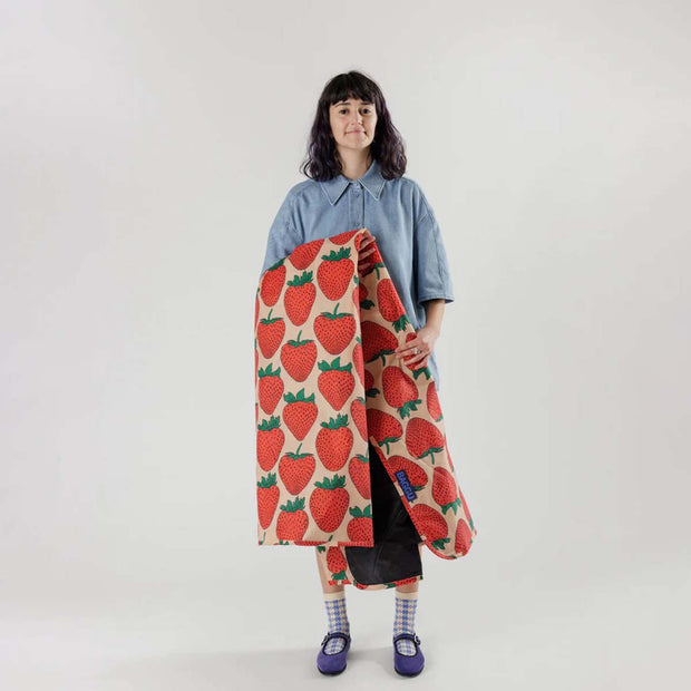 A person holding a Strawberry puffy picnic blanket from BAGGU