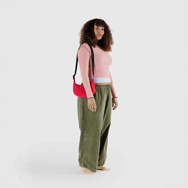 One small Crescent Bag from Baggu in Candy Apple worn over the shoulder
