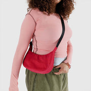 One small Crescent Bag from Baggu in Candy Apple worn crossbody