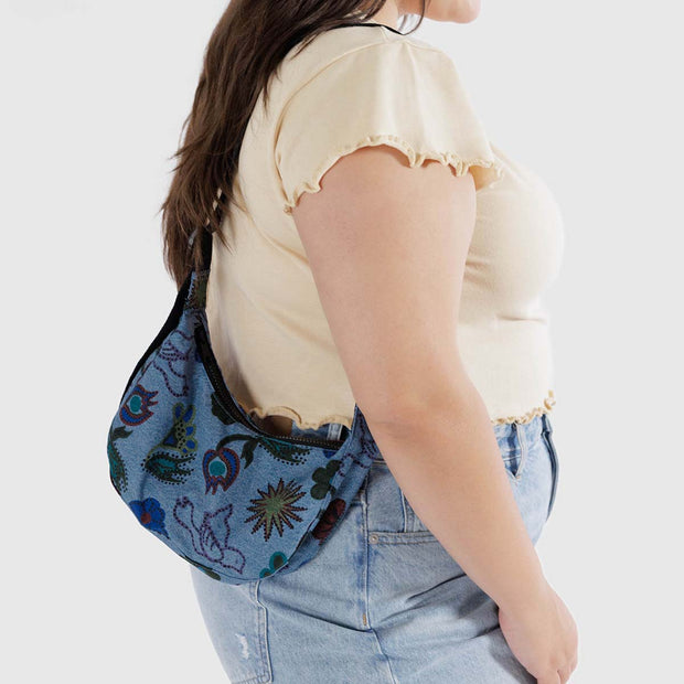 A close up of a person holding a small Crescent Bag from Baggu in Digital Denim Birds