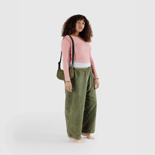 Baggu Small Crescent Bag in Seaweed with extended strap worn over a shoulder