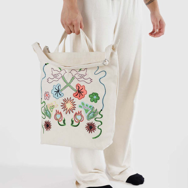 A close up of a person holding a Baggu Embroidered Birds Zip Duck Bag 