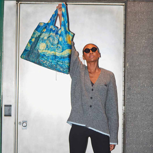 A person holding A Vincent Van Gogh recycled shopping bag featuring The Starry Night