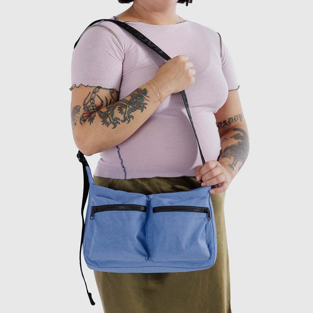 A close up of a person holding a Pansy Blue Medium Cargo Crossbody from Baggu