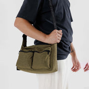 A close up of a person holding A Baggu medium cargo crossbody bag in Seaweed