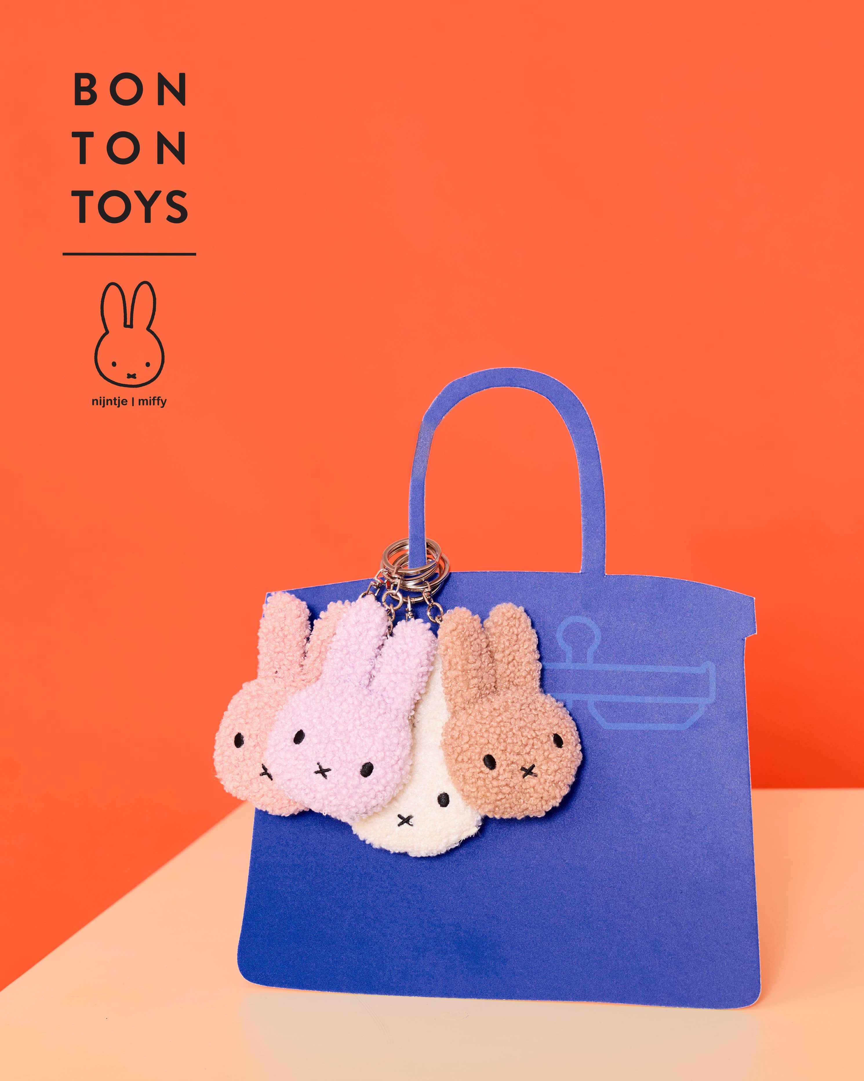 Blue handbag with four Miffy-shaped keychains on an orange background, featuring the Bon Ton Toys brand.
