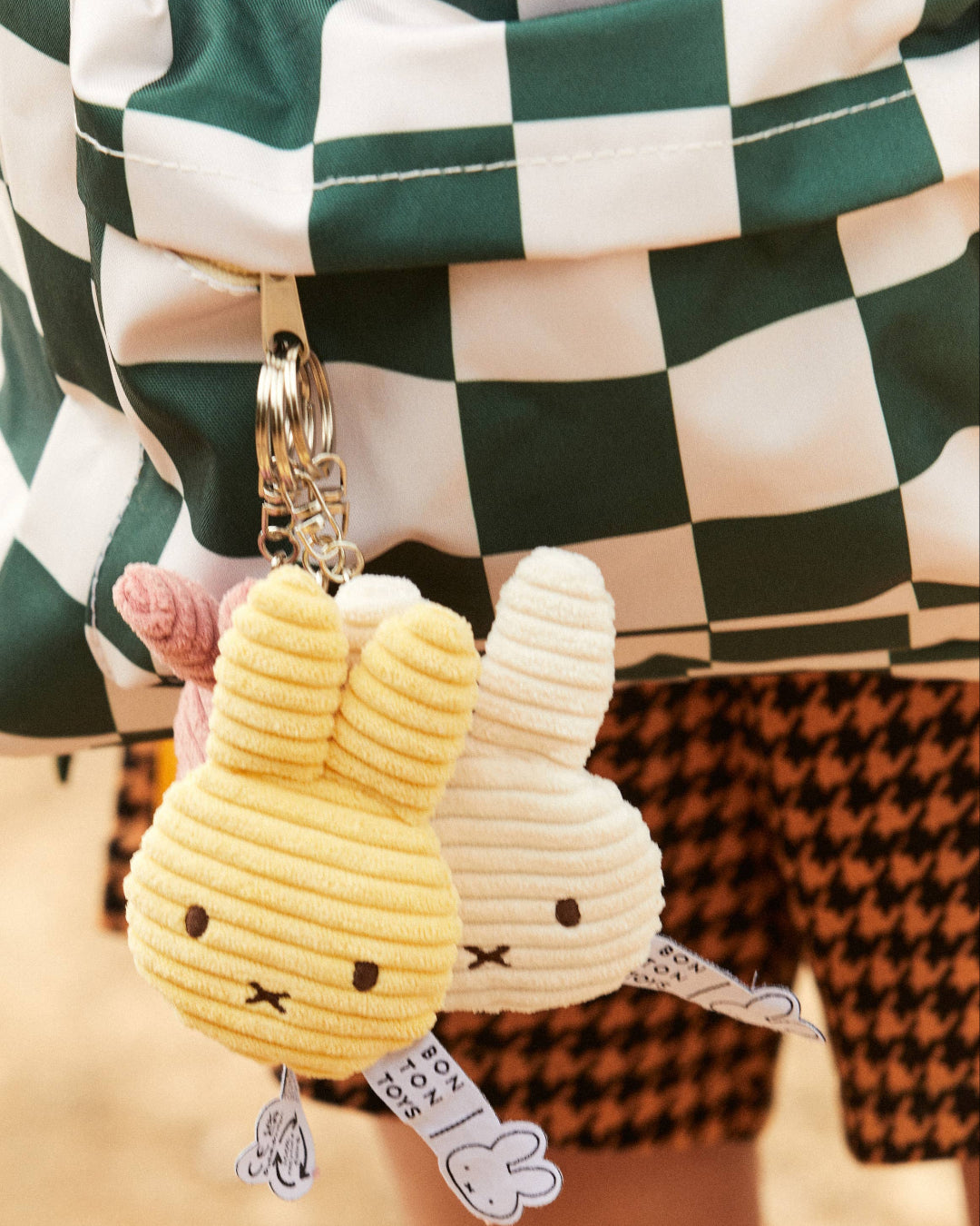 Three Miffy keychain, with a person wearing checkered pants in the background.